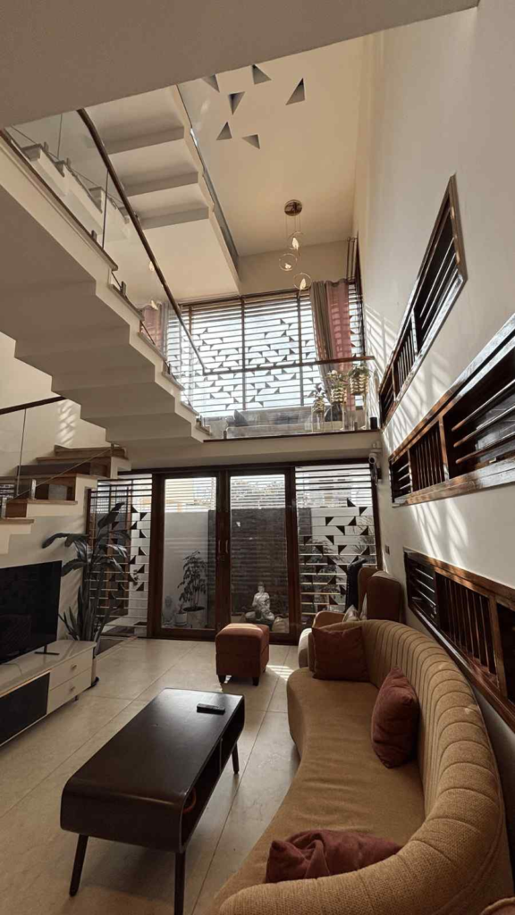 Spacious living room with double height ceiling, geometric ceiling pattern, and warm lighting designed by Elegante Interiors Bangalore