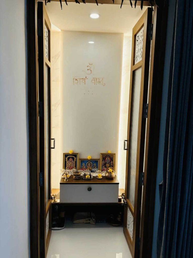 Contemporary pooja room design with backlit sacred wall panel and serene spiritual ambiance by Elegante Interiors