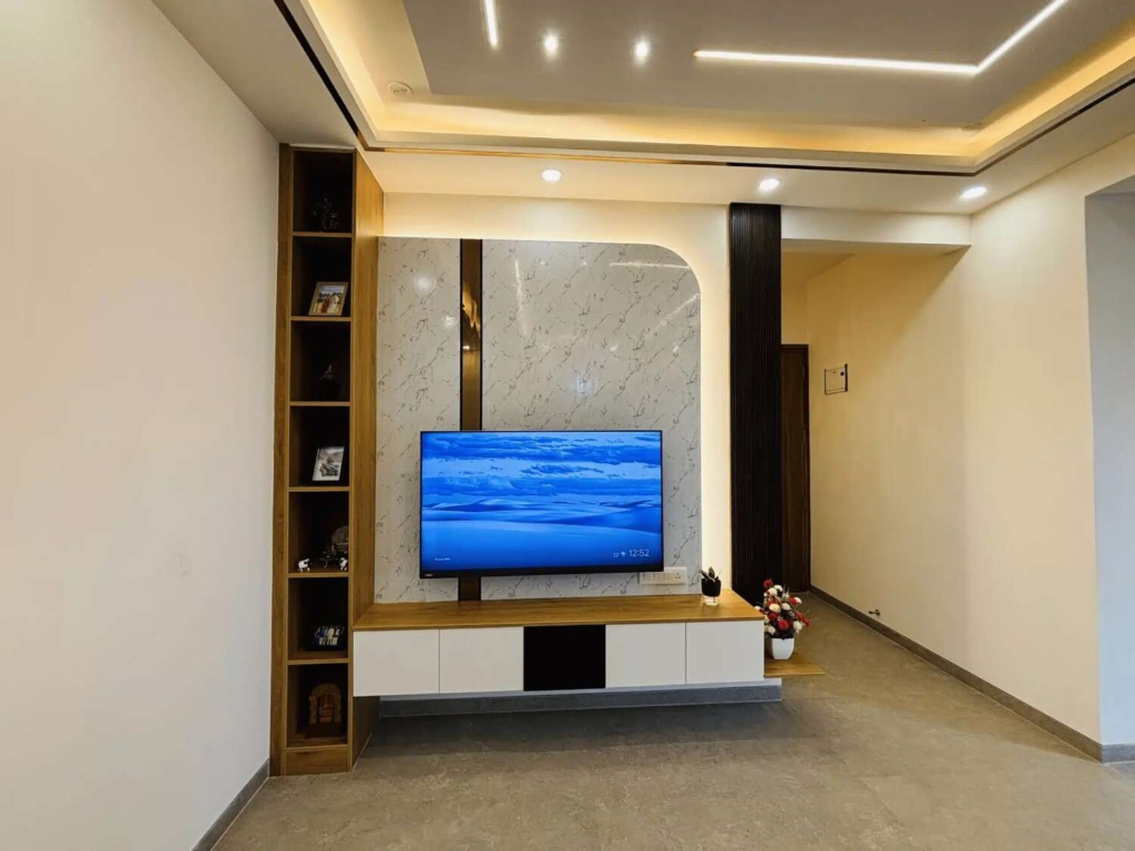 Sleek TV unit design with backlit marble panel, floating console, and integrated shelving by Elegante Interiors