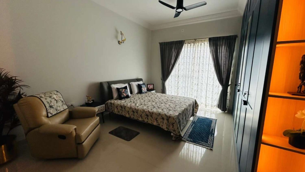 Elegant master bedroom interior design by Elegante Interiors featuring dark wood headboard, floral bedding, comfortable seating area, and warm ambient lighting