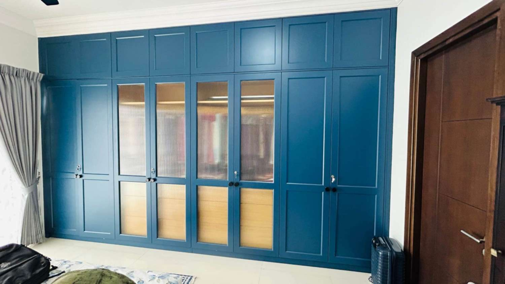 Custom designed wardrobe by Elegante Interiors featuring rich blue finish, glass panel inserts, and integrated lighting for Bangalore home interior