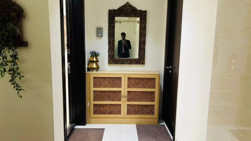 Elegant entrance console designed by Elegante Interiors with natural cane panel detailing, ornate mirror, and brass accents for sophisticated Bangalore home