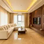 Luxury living room interior design in Bangalore with cove ceiling, marble flooring and custom TV unit by Elegante Interiors